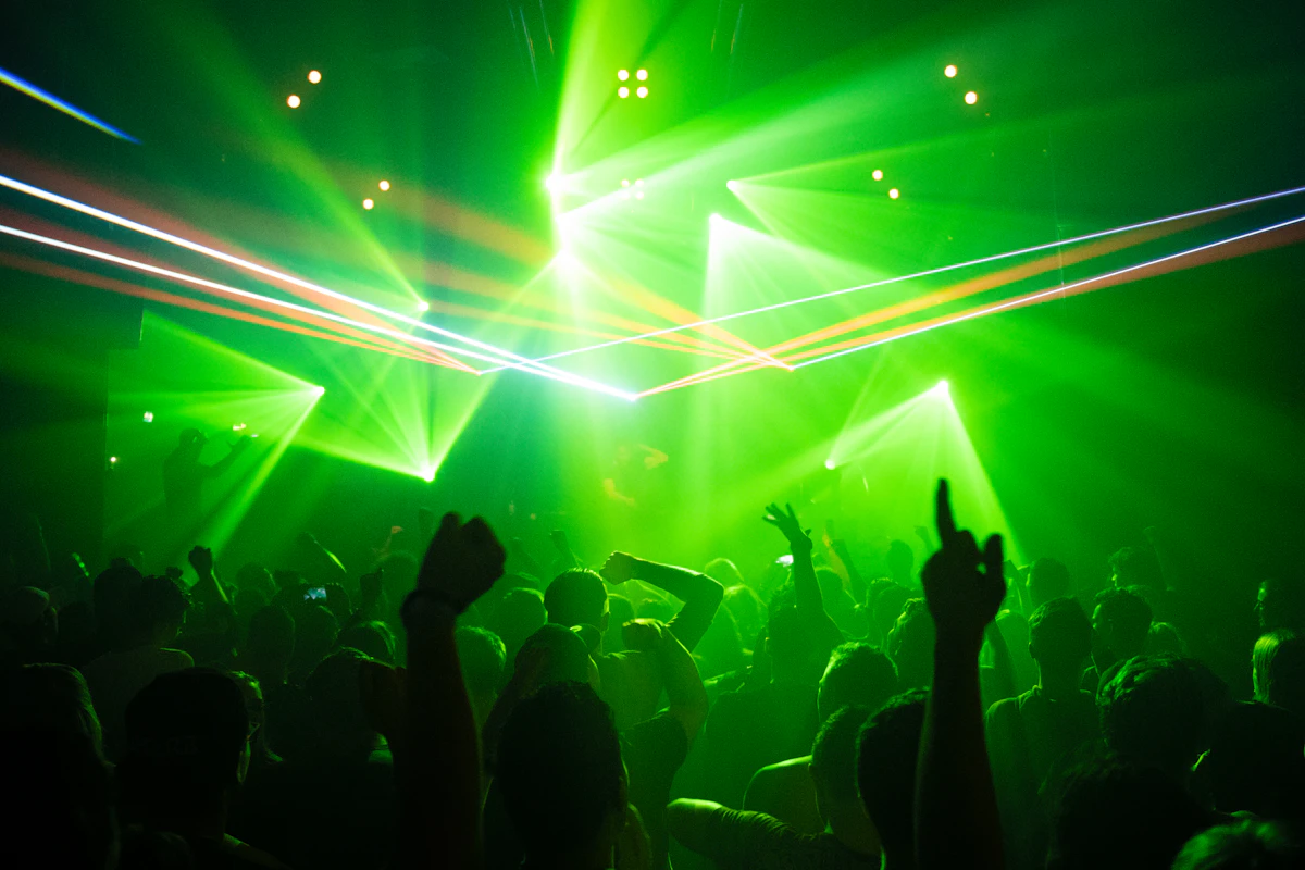 Nightclub crowd silhouetted beneath green stage lights
